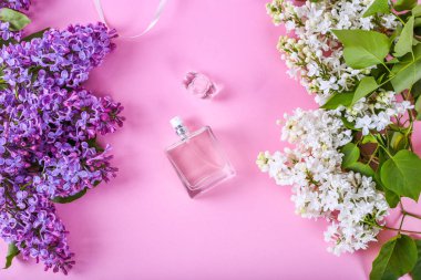 parfümeri ve çiçek kokusu kavramı. Pembe arka plan üzerinde llilac çiçekleri ile merkezinde parfüm şişesi. yaratıcı trendy düz metin için yer ile yatıyordu. leylak çiçekleri ile pembe bir arka plan üzerinde parfüm