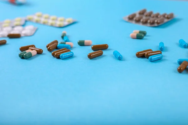 Pílulas coloridas espalhadas no fundo azul, vista superior — Fotografia de Stock