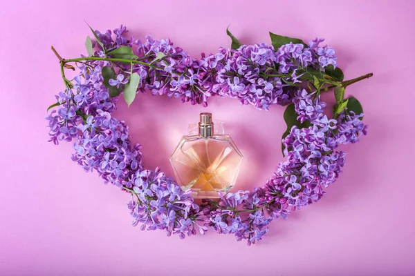 Profumeria e profumo floreale concetto. Elegante bottiglia di profumo di fiori lilla al centro su sfondo rosa . — Foto Stock