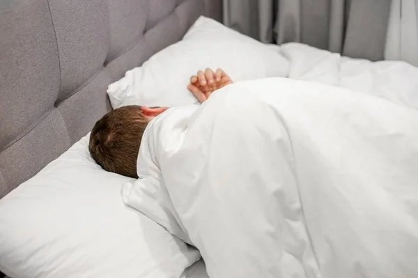 Homme dormant dans un lit blanc — Photo