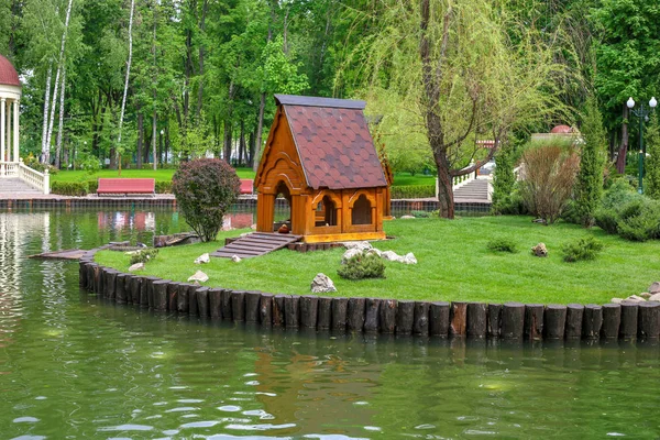 Duck house on the lake. Lake with arbor in city park. People have a rest in Park. Landscape design in city park.