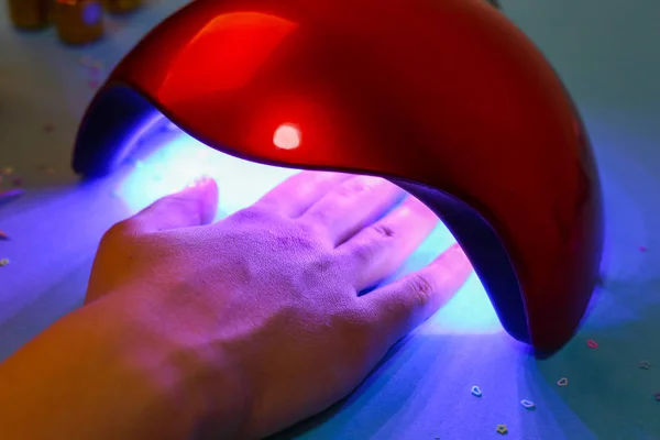 Lámpara UV gel pulido proceso de manicura en un salón de belleza. Procedimiento de salón. El maestro cubre las uñas del cliente con un barniz . — Foto de Stock