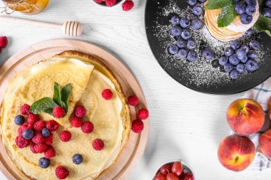 Ahududu ve yaban mersini ile krep üst görünümü. Sağlıklı yaz kahvaltısı, ev yapımı klasik Rus krep, sabah ışık arka plan, kopya alanı, üst görünüm. Rus ince krep blini yığını