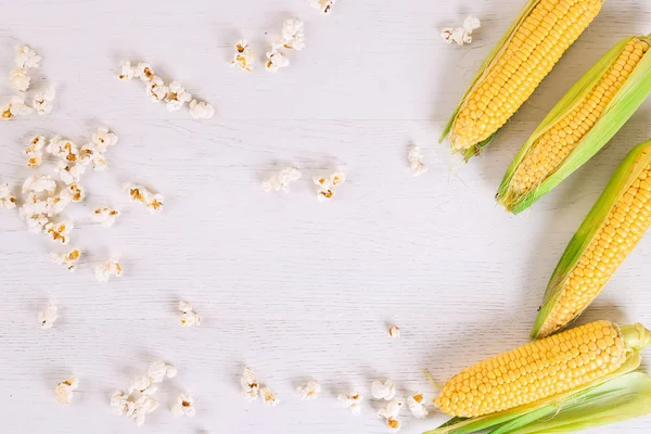Свежая кукуруза и попкорн на деревянном белом фоне. Принято. Плоский лежал — стоковое фото