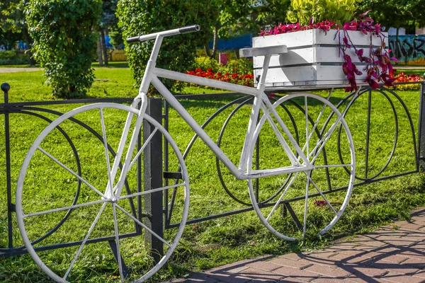 Beautiful white bike with flowers on a background of green park. Summer.Beautiful colorful flowers on white bicycle concept of wedding and valentine landscape in the garden background
