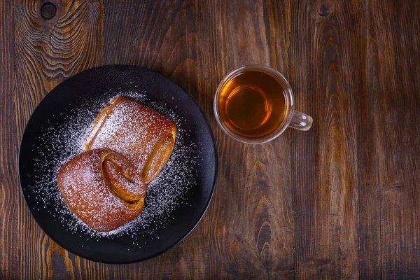 Zwei leckere Brötchen mit einer Tasse Tee. leckeres Frühstück, süße Brötchen und schwarzer Tee. flache Lage, Draufsicht. — Stockfoto