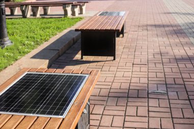 Sokakta güneş paneliyle halka açık bankta hücum. Alternatif elektrik kaynağı ve modern teknoloji kavramı. Güneş paneli olan akıllı bank