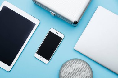 Ofis masaları dizüstü bilgisayar, tablet pc, cep telefonu, hoparlör ve çanta yükü. kopya mavi alanı düz bırakır