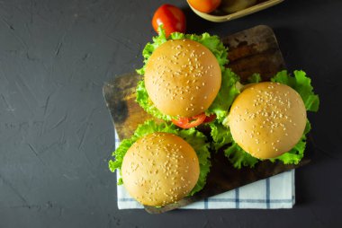 Ev yapımı hamburger domuz eti, soğan, domates, marul ve peynir rustik koyu arka plan üzerinde. üstten görünüm