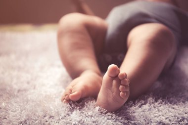 Yeni doğan Asya bebek beyaz tüylü kumaş üzerinde uyku ayak