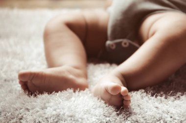 Yeni doğan Asya bebek beyaz tüylü kumaş üzerinde uyku ayak