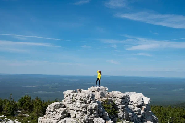一个穿着亮夹克的男人站在山顶上 地球的规模 图库照片