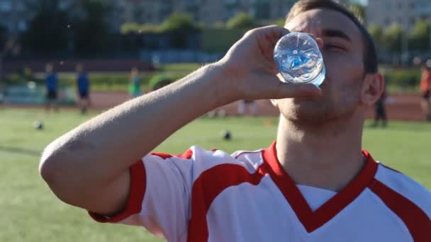 Footballeur fatigué boit une eau pendant la formation — Video