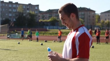 Yorgun oyuncu eğitim sırasında bir su içiyor