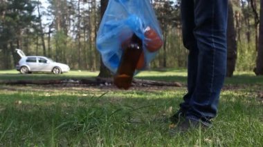 Bir adam çöp içinde belgili tanımlık geçmiş ormandaki bir araba atar.