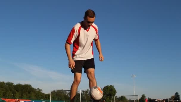 Eğitim ve bir futbol topu bacaklarının üzerinde zıplayan futbolcu — Stok video