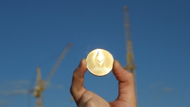 Moneta Ethereum in mano sullo sfondo di gru da costruzione, primo piano, moneta Ethereum — Video Stock