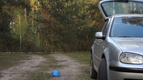 Un homme jette déchets, ordures, plastique du coffre de la voiture, pollution de la nature — Video