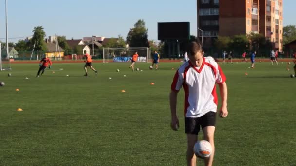 Jogador de futebol está treinando e saltando uma bola de futebol em sua perna — Vídeo de Stock