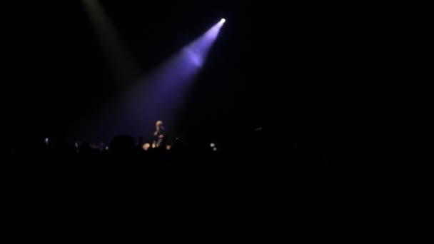 De zanger zingt op het podium, het wordt verlicht door schijnwerpers — Stockvideo