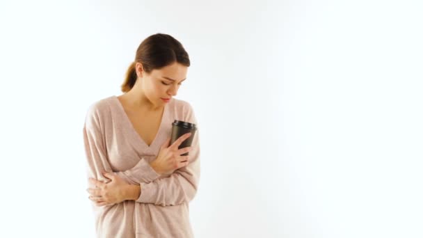 Bonita chica morena bebe de una taza de té y mirando a la cámara, aislada — Vídeos de Stock