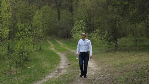 Homem Caminha Pela Floresta Bebe Água Uma Garrafa Uma Estrada — Vídeo de Stock