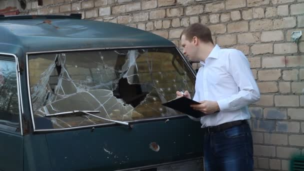 Hombre inspecciona un coche roto minibús, seguro — Vídeo de stock