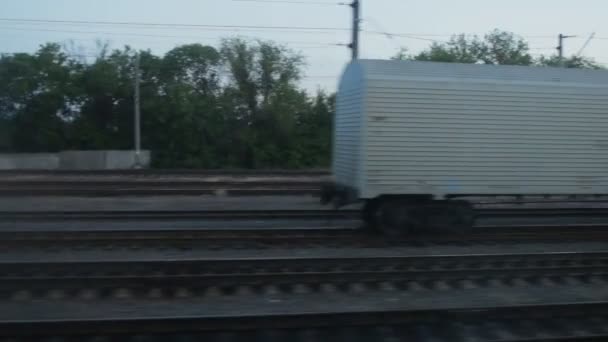 Vue de la fenêtre du train, un wagon de marchandises blanc se tient sur le chemin de fer — Video