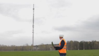 Bir adam Müfettiş bir dizüstü bilgisayarda yazdırır ve televizyon kulesi denetler