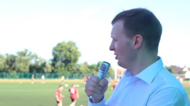 Futbol bir futbol maçı arka planda bir mikrofon Yorumlar ile beyaz bir gömlek, erkek bir yorumcu