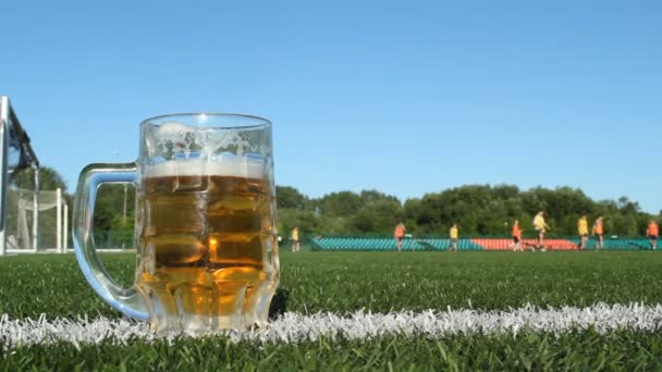 Bir bardak bira bir futbol sahasında, stadyumda futbol oynanır — Stok video