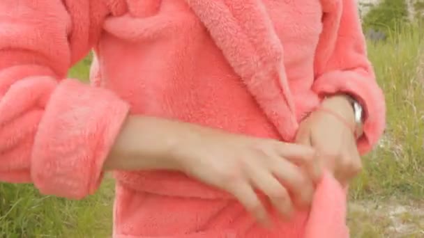 Девушка завязывает розовый халат на открытом воздухе — стоковое видео