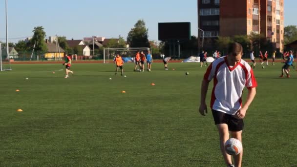 Voetballer is opleiding en stuiteren een voetbal door zijn been — Stockvideo