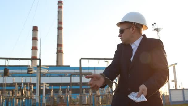 The engineer inspector in handcuffs keeps money against the background of the power plant and is indignant — Stock Video