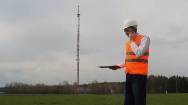 Telefonla kötü baş mühendis küfürler işçiler, bir telefon kulesi arka planı üzerinde