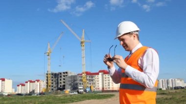 Bir ev inşa zemin üzerine beyaz bir kask denetçisinde siyah gözlük kaldırır ve gözleri, yorgunluk losyonları