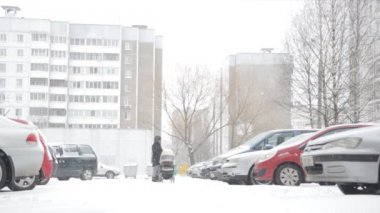 Annesiz bir çocuk arabasındaki bebek ile yoğun bir kar yağışı içinde yürür