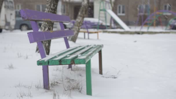 Banco en un patio de la ciudad fuerte nevada, ventisca, invierno — Vídeo de stock