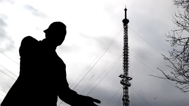 Um homem está falando ao telefone no fundo de uma torre telefônica, conexão móvel — Vídeo de Stock