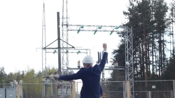 A young engineer inspector dances and rejoices against the background of a power plant — Stock Video