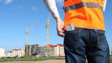 Bir adam Müfettiş patron pantolonunun arka cebinden para dolar dışarı alır ve arka plan inşaat anlatıyor