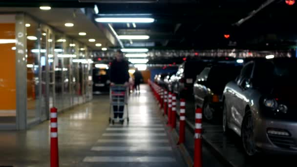 En ung man med en vagn går på en underjordisk parkering för shopping i ett shoppingcenter, koncept — Stockvideo