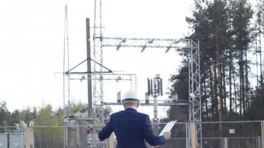 Genç bir mühendis Müfettiş dans ediyor ve bir santral arka planı sevinir