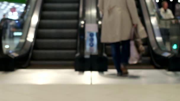 People climb and ride on an escalator inside a shopping center, blurred, moving staircase — Stock Video