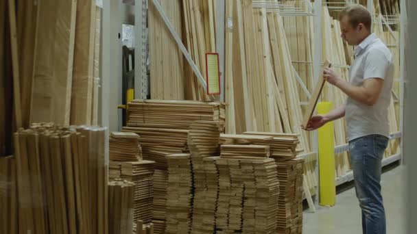 Покупатель выбирает деревянные доски в хозяйственном магазине — стоковое видео