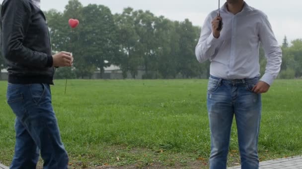 A man is giving a heart to another man, but he refuses, homosexuality, slow-mo, it is raining outside — Stock Video