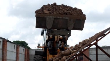 Büyük bir yükleyici kepçe kum kum taşlardan ayırmak için tohum matkap üzerinde taşlarla dışarı dökülen sower