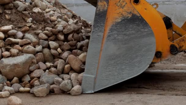 En stor gul lastare samlar krossad sten i en hink, närbild, stenar och traktor — Stockvideo