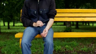 Bir adam bir parkta bir bankta oturur ve damarlar, depresyon kolunda, intihar hakkında düşünüyor damarlar yakınındaki bir bıçak kesme tutar