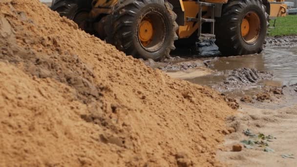 Колёса большого желтого вилочного погрузчика по грязи, медленному движению, колесным погрузчикам и грязи — стоковое видео